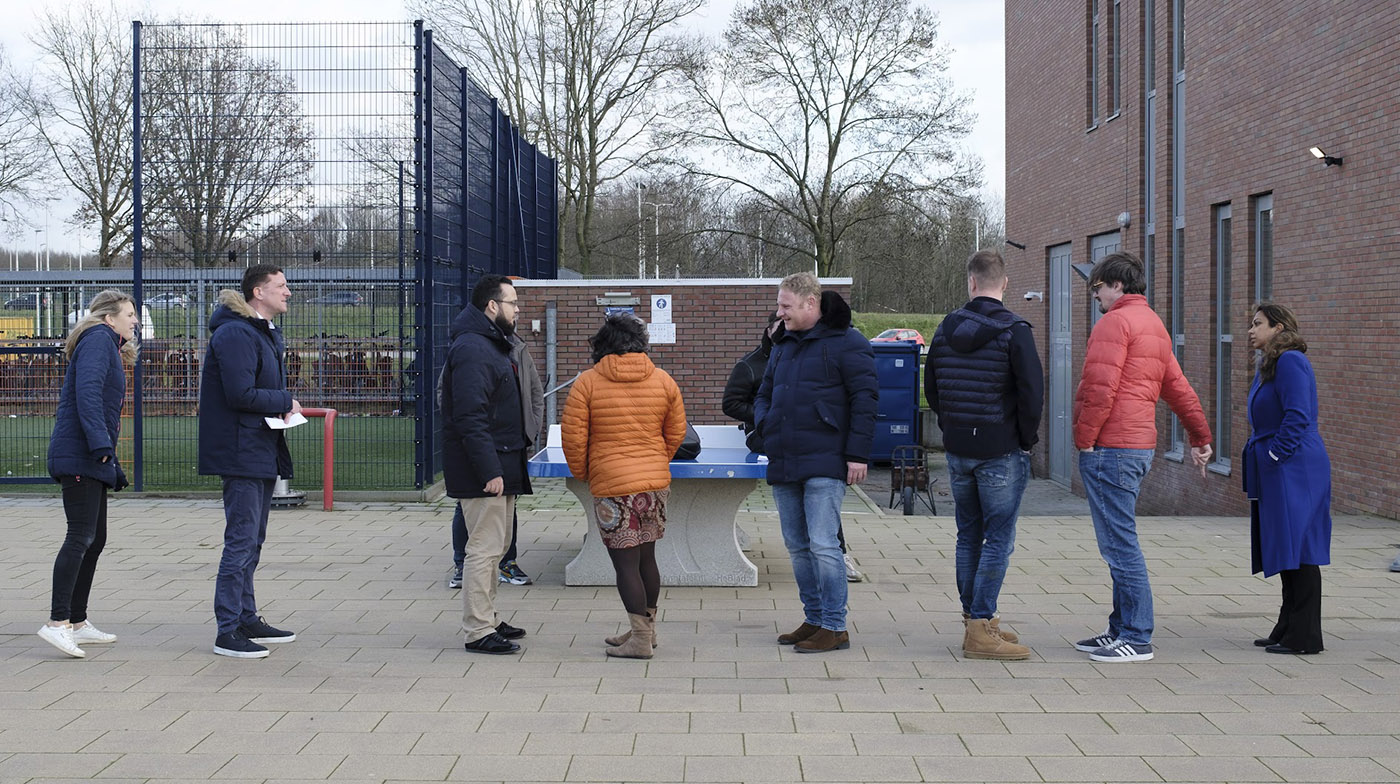 Leraar voor de klas met andere leraren in de schoolbanken